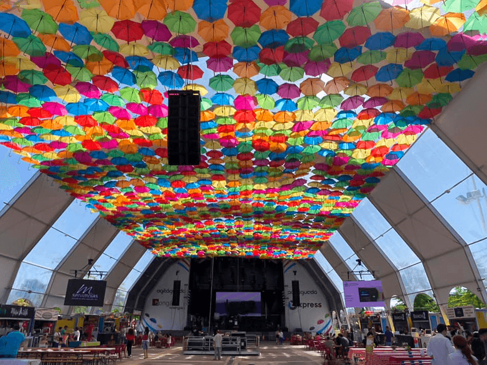 Photograph of orbital igloo tent with alternating white and transparent tops and main stage for the Agitágueda 2023 event.